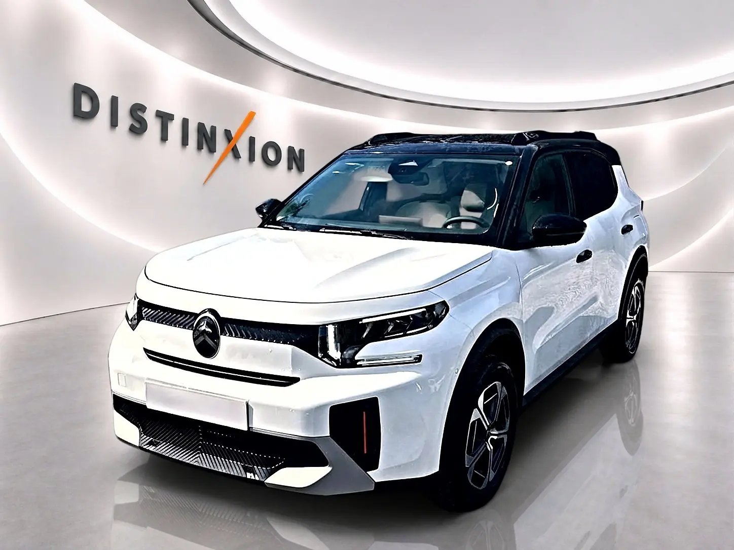 Citroën C3 Aircross blanc vue 3/4 avant droit avec toit noir et jantes alu dans showroom lumineux.