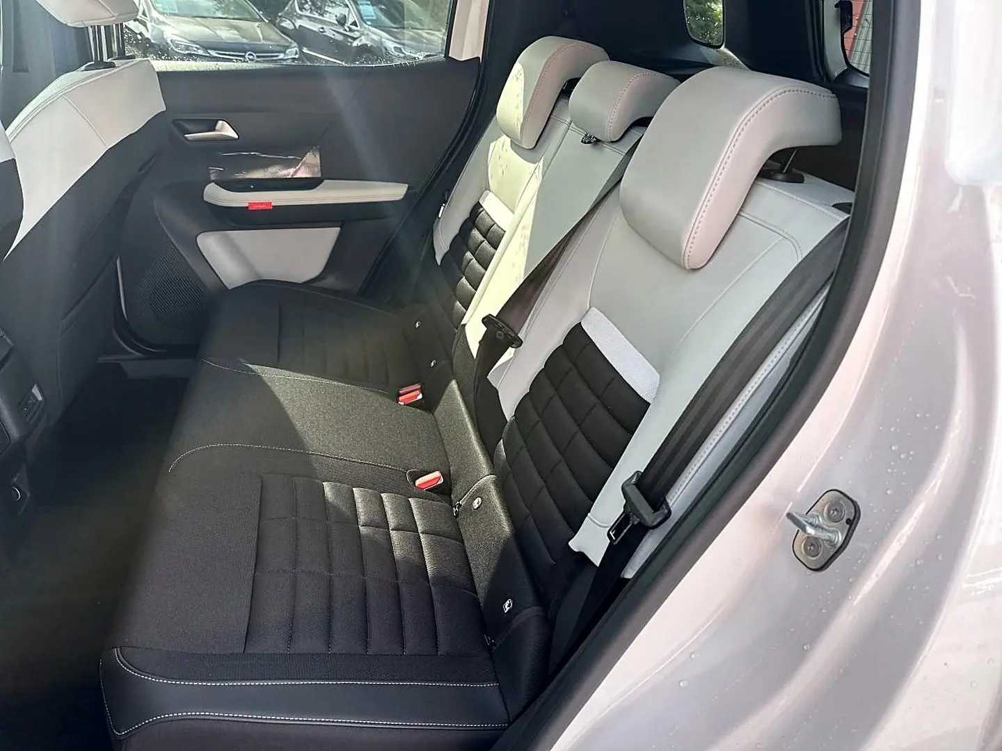 Vue côté droit sur la banquette arrière bicolore noire et blanche du Citroën C3 Aircross blanc, avec porte ouverte.