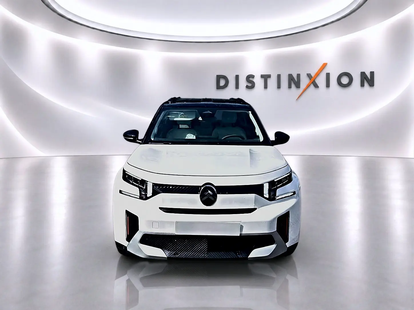 Vue frontale d'un Citroën C3 Aircross blanc avec toit noir, dans un studio lumineux au logo Distinxion en arrière-plan.