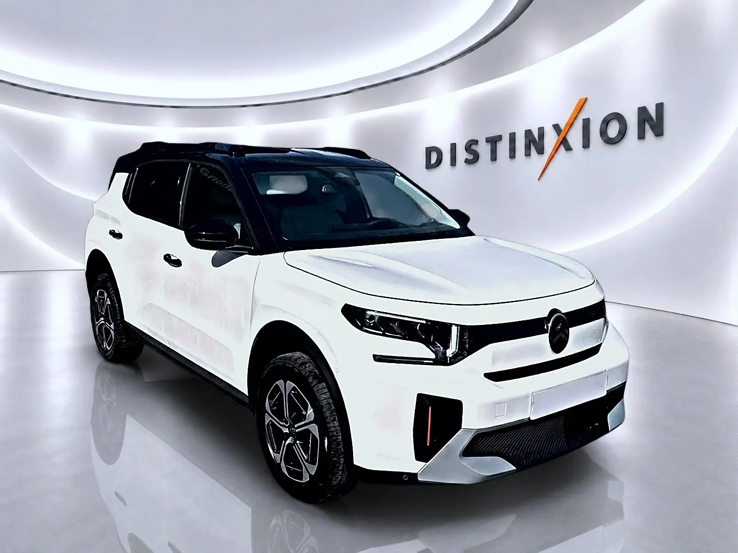 Citroën C3 Aircross blanc en 3/4 avant droit avec toit noir et jantes alu distinctives dans un showroom.