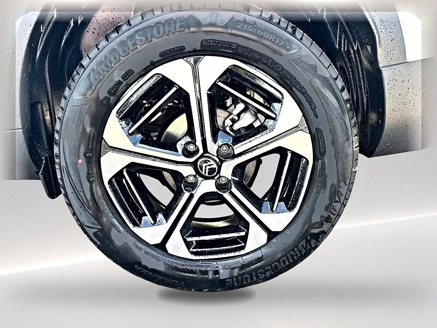 Gros plan sur la jante alu bicolore noire et argent du côté gauche d’un Citroën C3 Aircross blanc 2026.