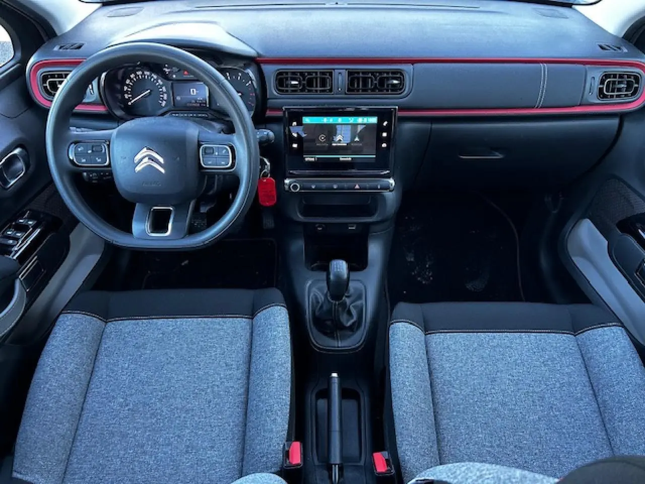 Intérieur avant de la Citroën C3 gris foncé, volant multifonction, tableau de bord avec écran tactile central et sellerie tissu gris.