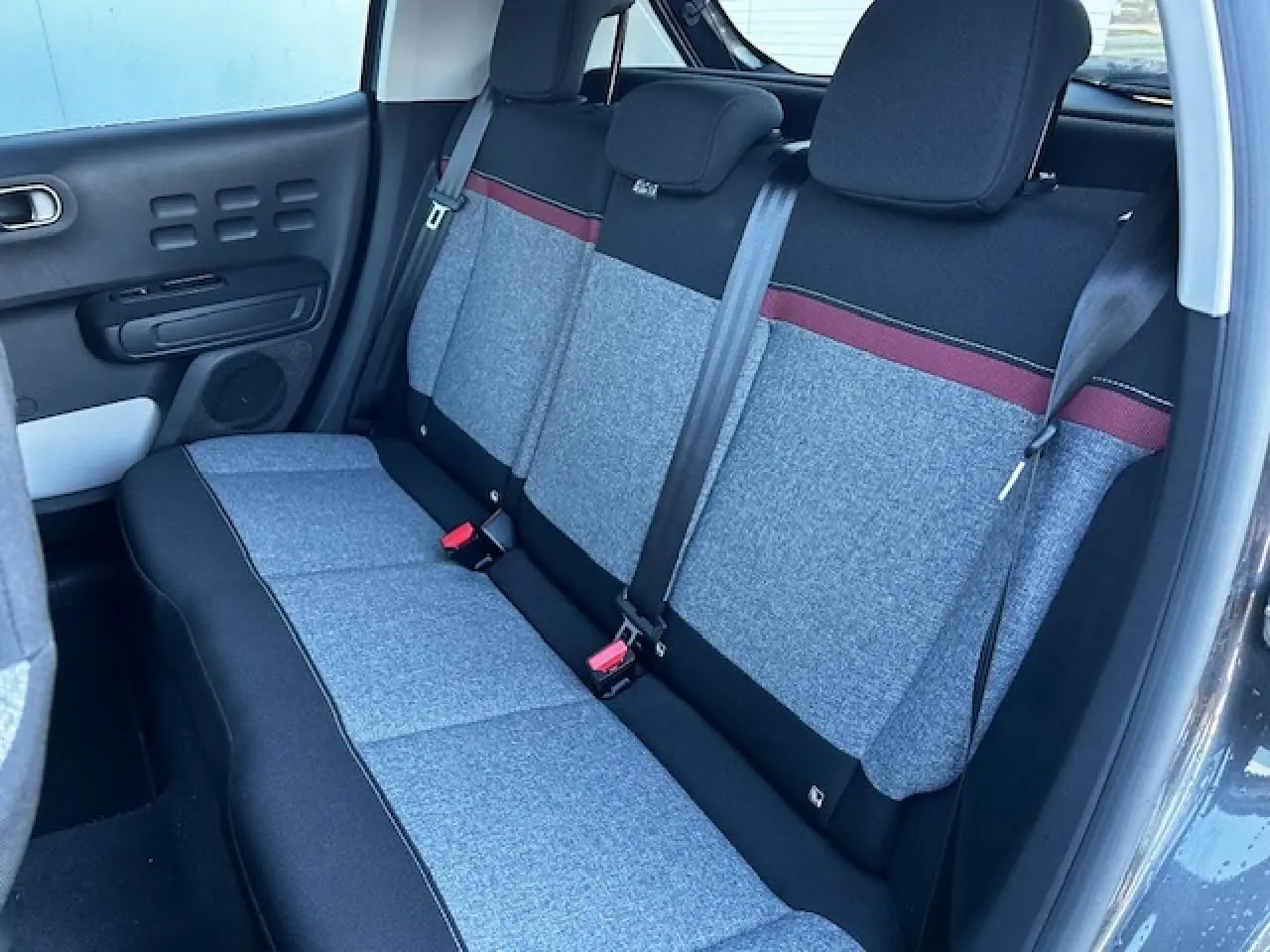 Banquette arrière grise avec bande rouge dans une Citroën C3 III vue côté gauche, intérieur clair et moderne.