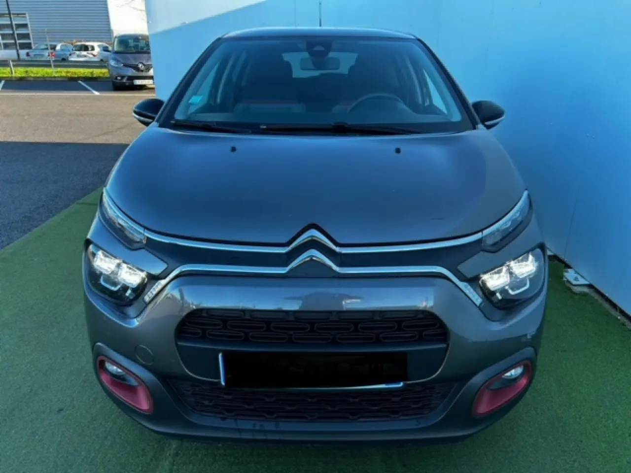 Vue frontale d'une Citroën C3 gris foncé avec signature lumineuse LED et entourages rouges sur le pare-chocs.