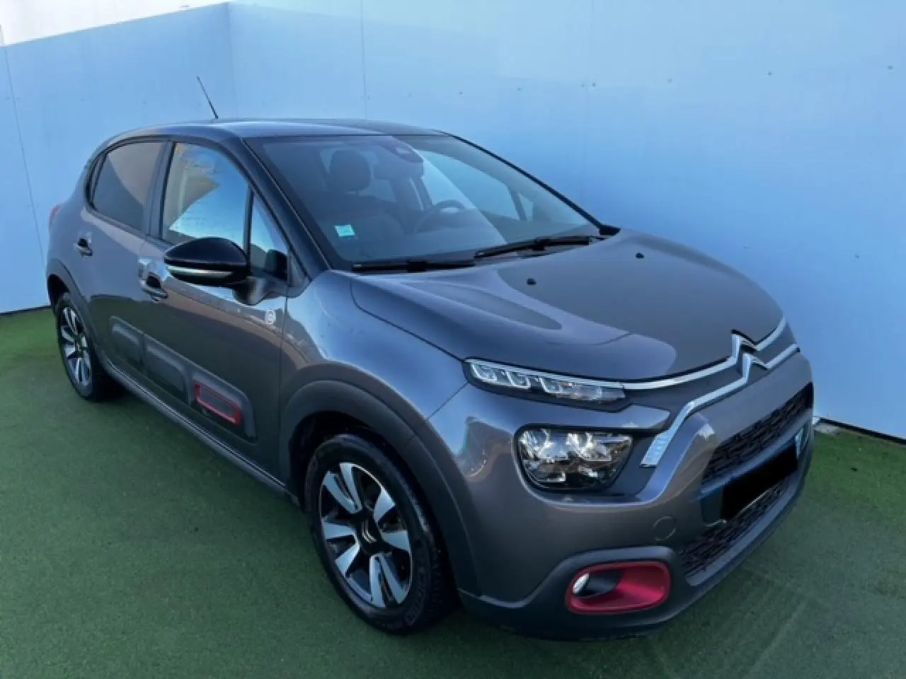 Citroën C3 gris foncé vue 3/4 avant droit avec inserts rouges sur pare-chocs et protections latérales