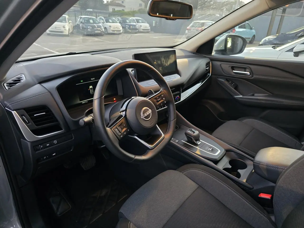 Intérieur du Nissan Qashqai 2024 vu côté conducteur, volant cuir et écran tactile central visible.
