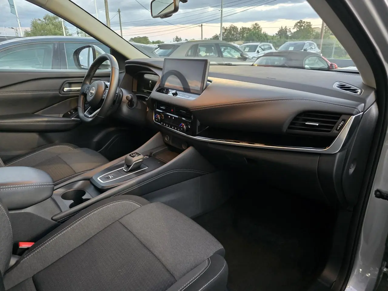Intérieur du Nissan Qashqai 2024 gris silver, vue côté passager montrant tableau de bord et console centrale moderne.