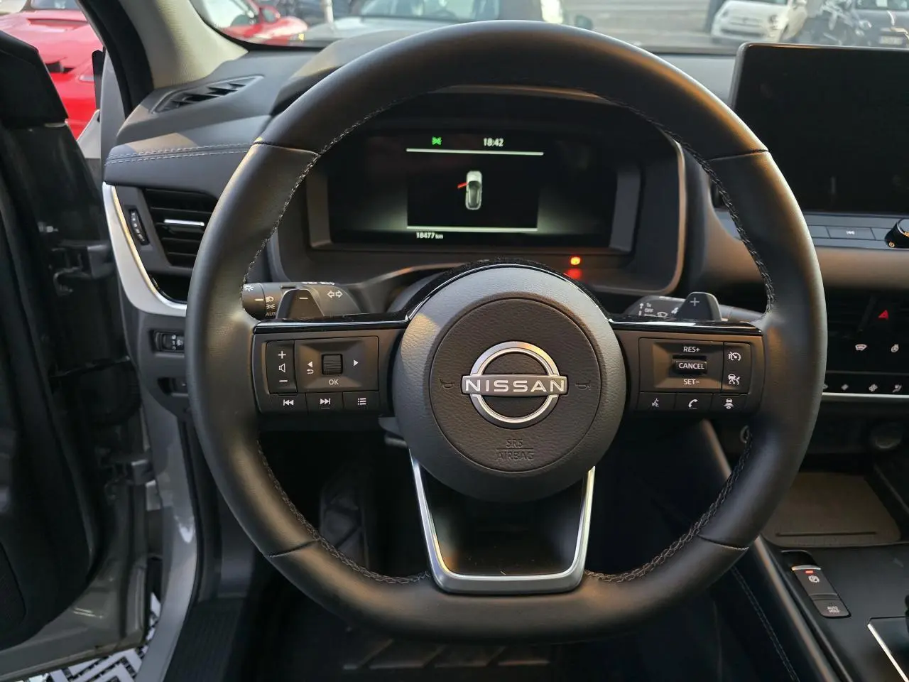 Vue centrée sur le volant cuir du Nissan Qashqai gris silver 2024, avec commandes intégrées et tableau de bord numérique.