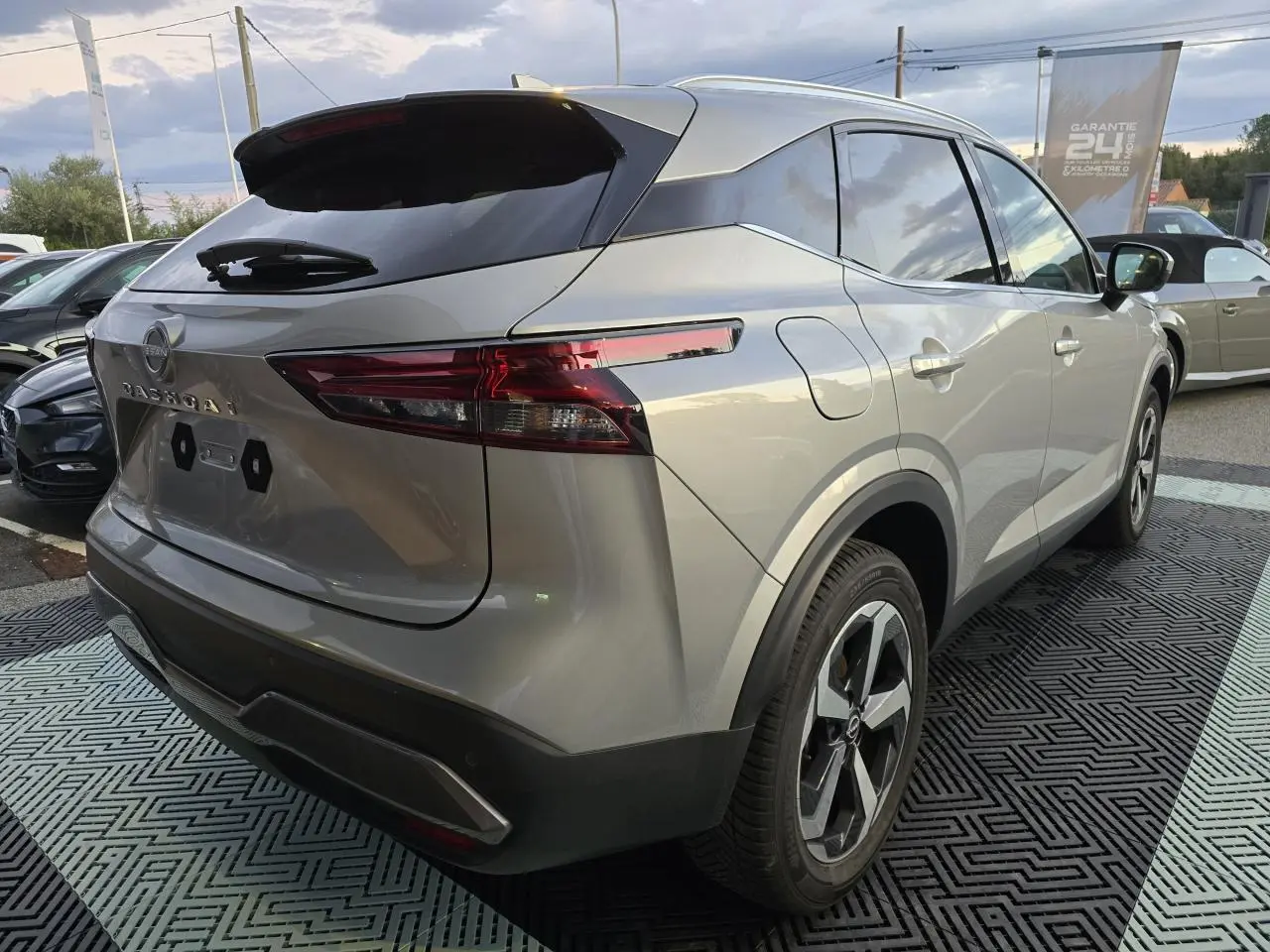 Vue 3/4 arrière droite du Nissan Qashqai gris silver 2024 avec feux LED et jantes alliage 18 pouces.
