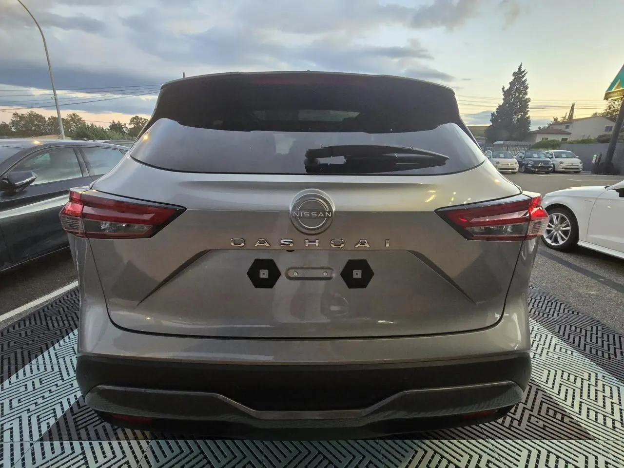 Vue arrière du Nissan Qashqai gris silver 2024 avec feux LED et hayon électrique sans plaque visible.
