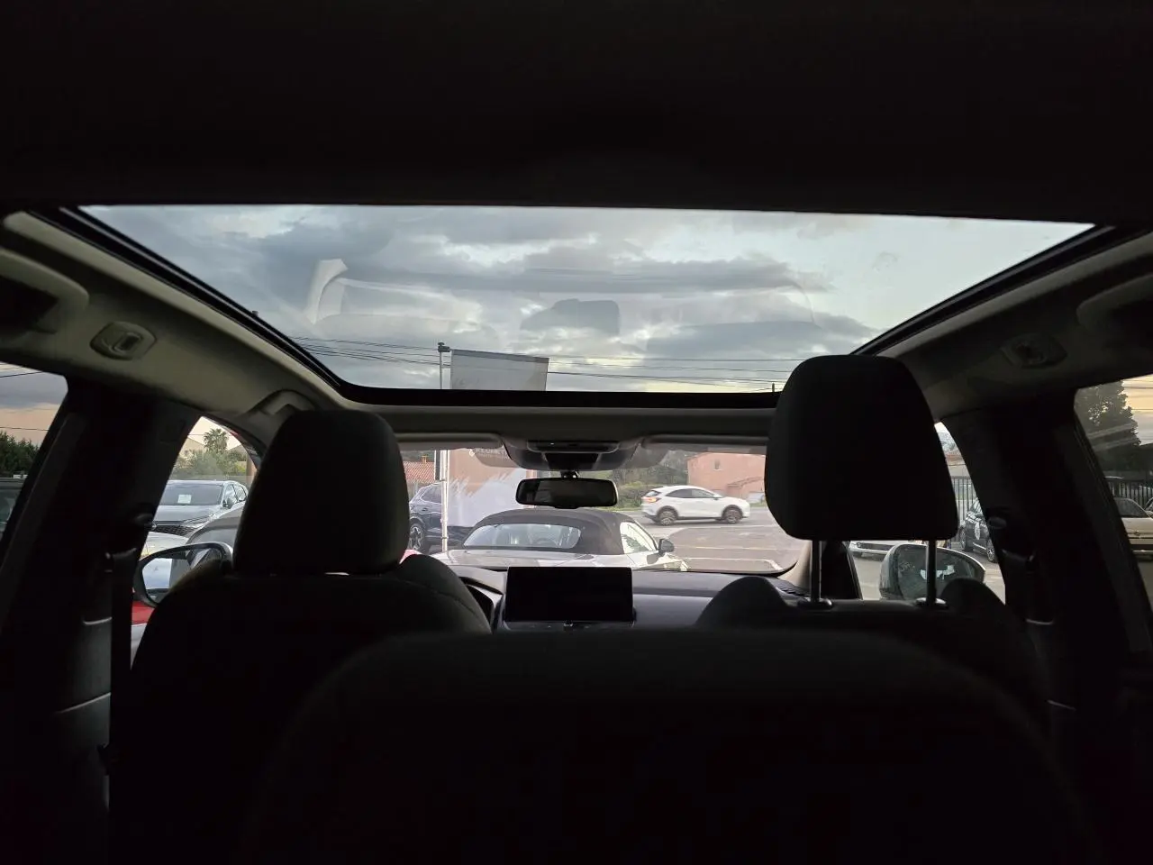 Vue intérieure arrière du Nissan Qashqai gris silver 2024 avec toit panoramique et sièges avant noirs.
