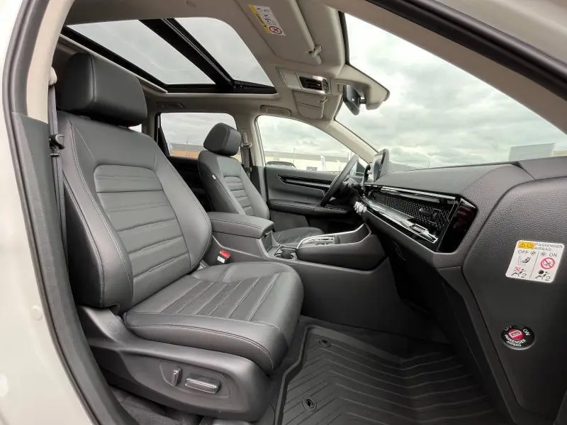 Intérieur avant du Honda CR-V blanc, sièges cuir noirs, toit panoramique et tableau de bord moderne visible côté passager.