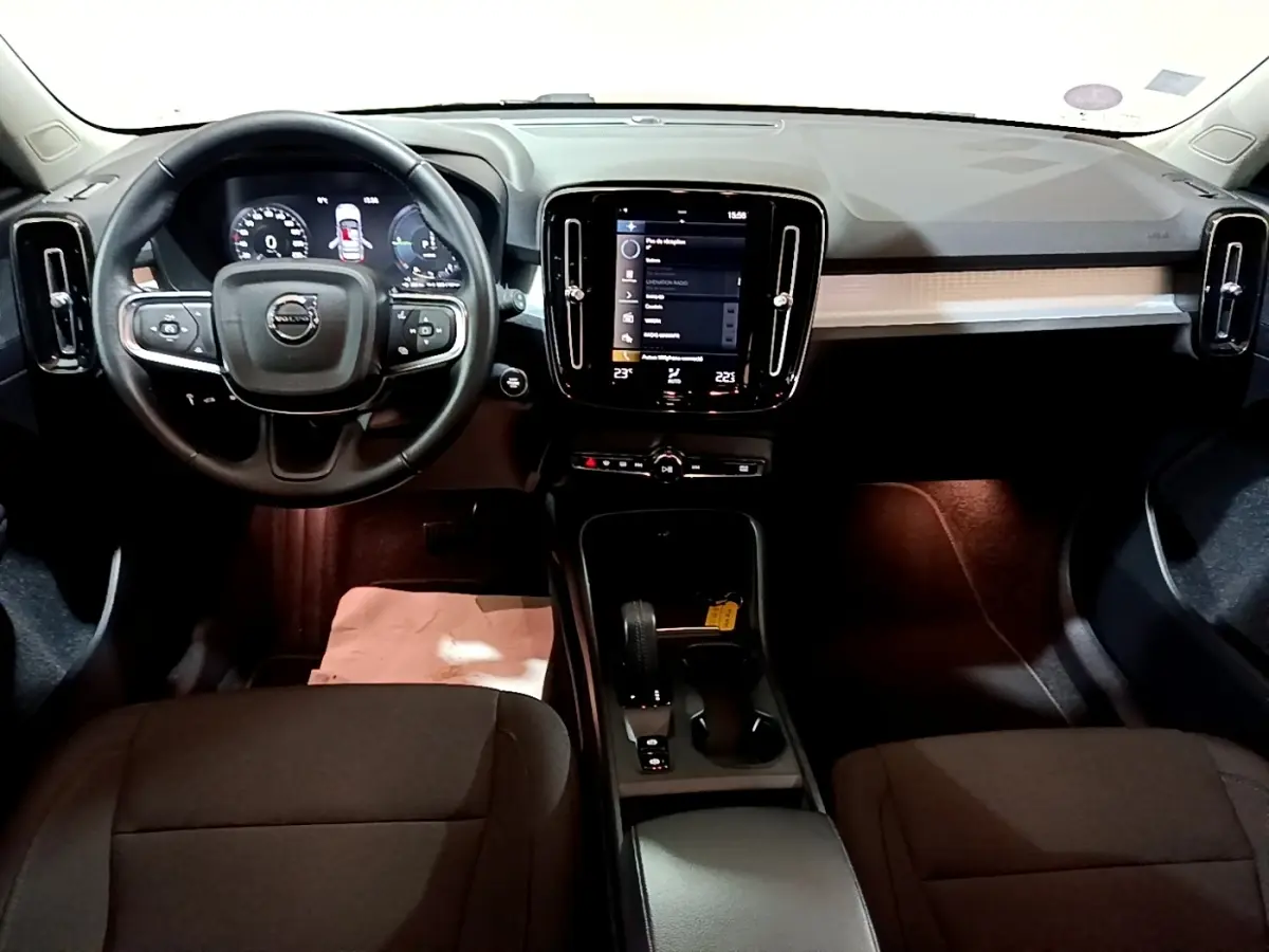 Vue intérieure frontale du tableau de bord noir du Volvo XC40 Recharge T4 avec écran tactile central et volant multifonctions.