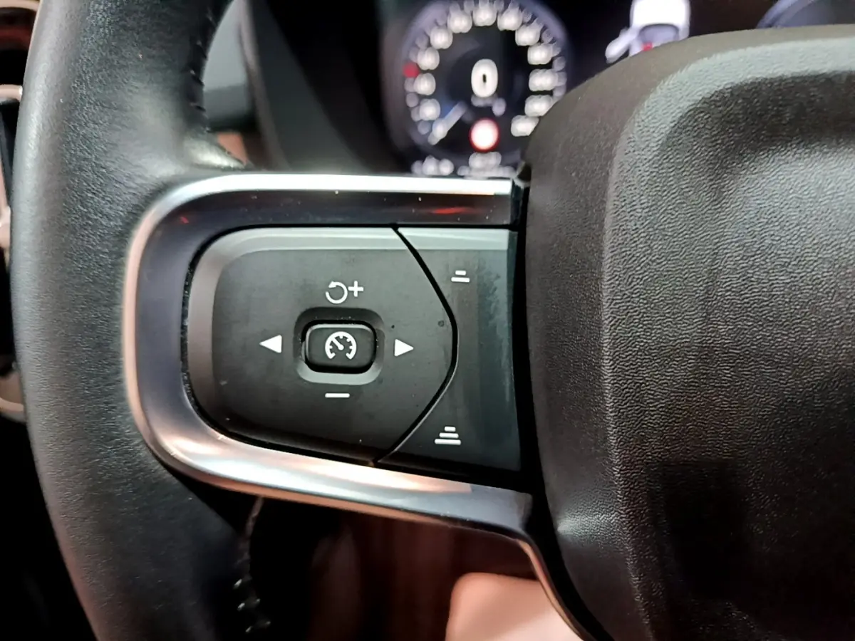 Gros plan sur les commandes de régulateur de vitesse au volant cuir noir du Volvo XC40 Recharge T4 Business 2020.