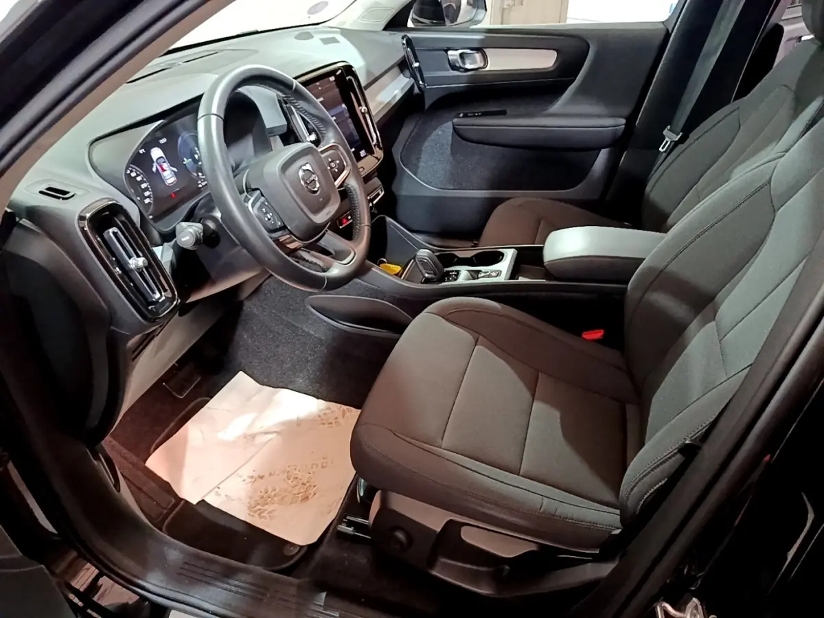 Intérieur avant droit du Volvo XC40 noir 2020, avec tableau de bord numérique et sièges tissu gris foncé.
