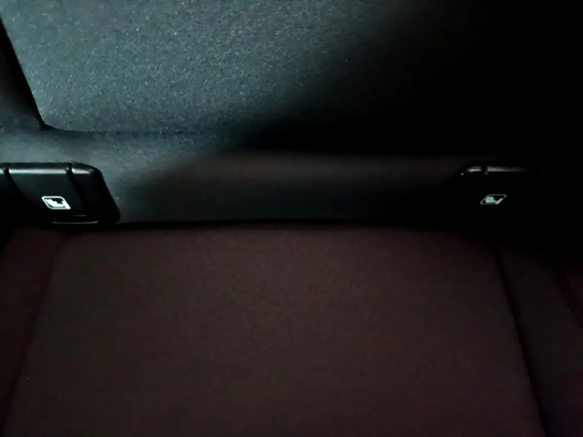 Détail de la banquette arrière noire du Volvo XC40 Recharge T4, montrant les commandes de rabattement des sièges.