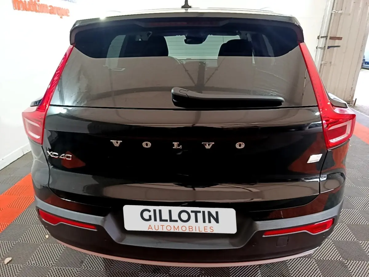 Vue arrière d'un Volvo XC40 noir avec feux arrière en forme de C et logo VOLVO bien visible sur le hayon.