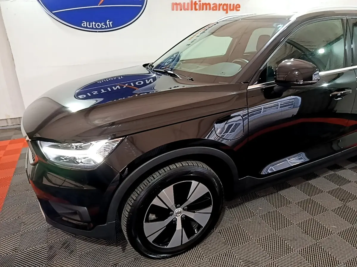 Vue 3/4 avant gauche du Volvo XC40 noir hybride rechargeable, mettant en valeur ses phares LED et jantes distinctives.