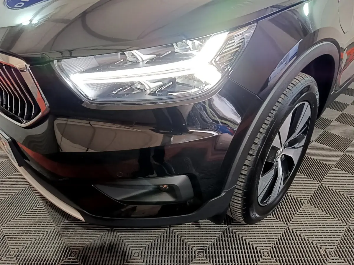 Gros plan sur l'avant droit noir du Volvo XC40 Recharge T4 avec phare LED et jante alliage distinctive.