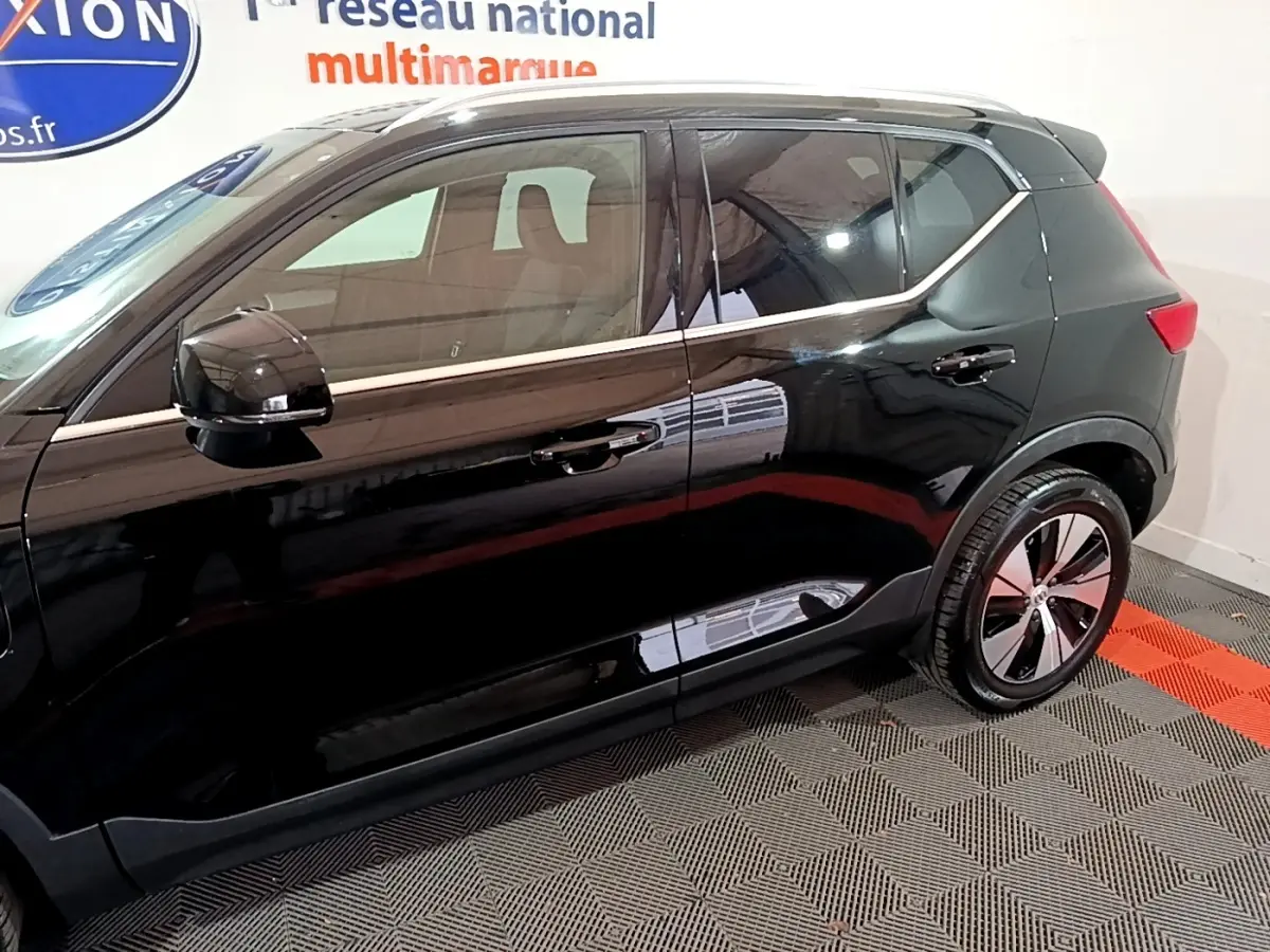Vue latérale côté gauche du Volvo XC40 Recharge T4 Business noir, soulignant ses jantes modernes et la ligne chromée au-dessus des portières.