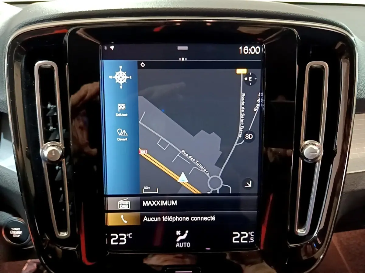 Écran tactile central affichant la navigation dans un Volvo XC40 noir, avec ventilation et bouton démarrage visibles.