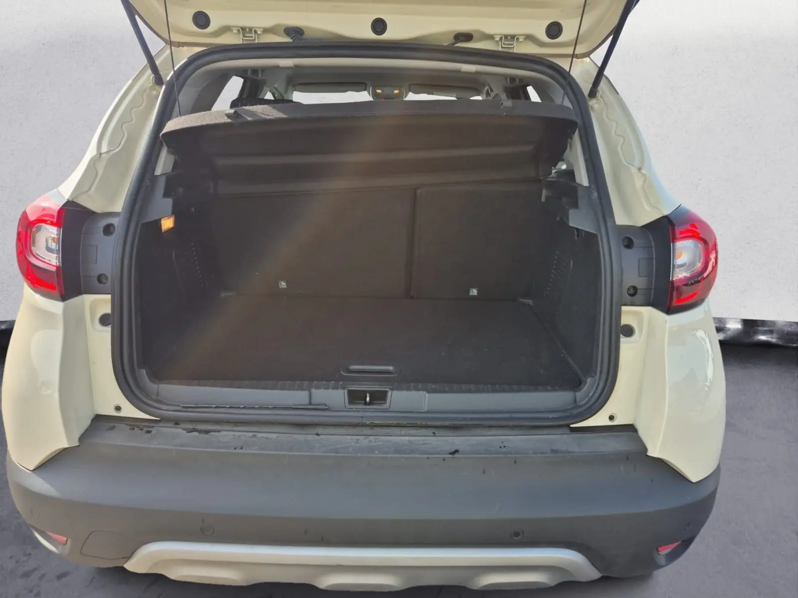Vue arrière du coffre ouvert d'un Renault Captur beige/marron 2018, montrant l'espace de chargement vide.