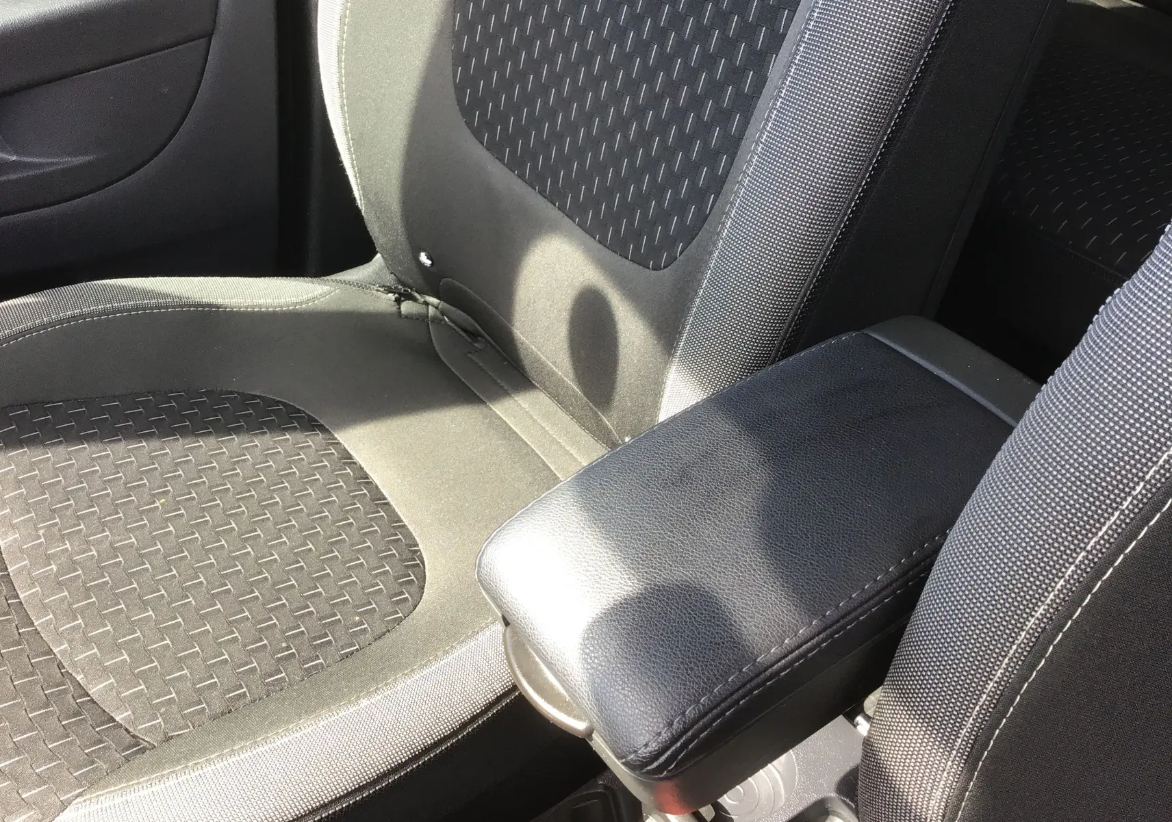 Gros plan sur les sièges avant noirs et gris du Renault Captur 2018 avec accoudoir central en cuir noir.