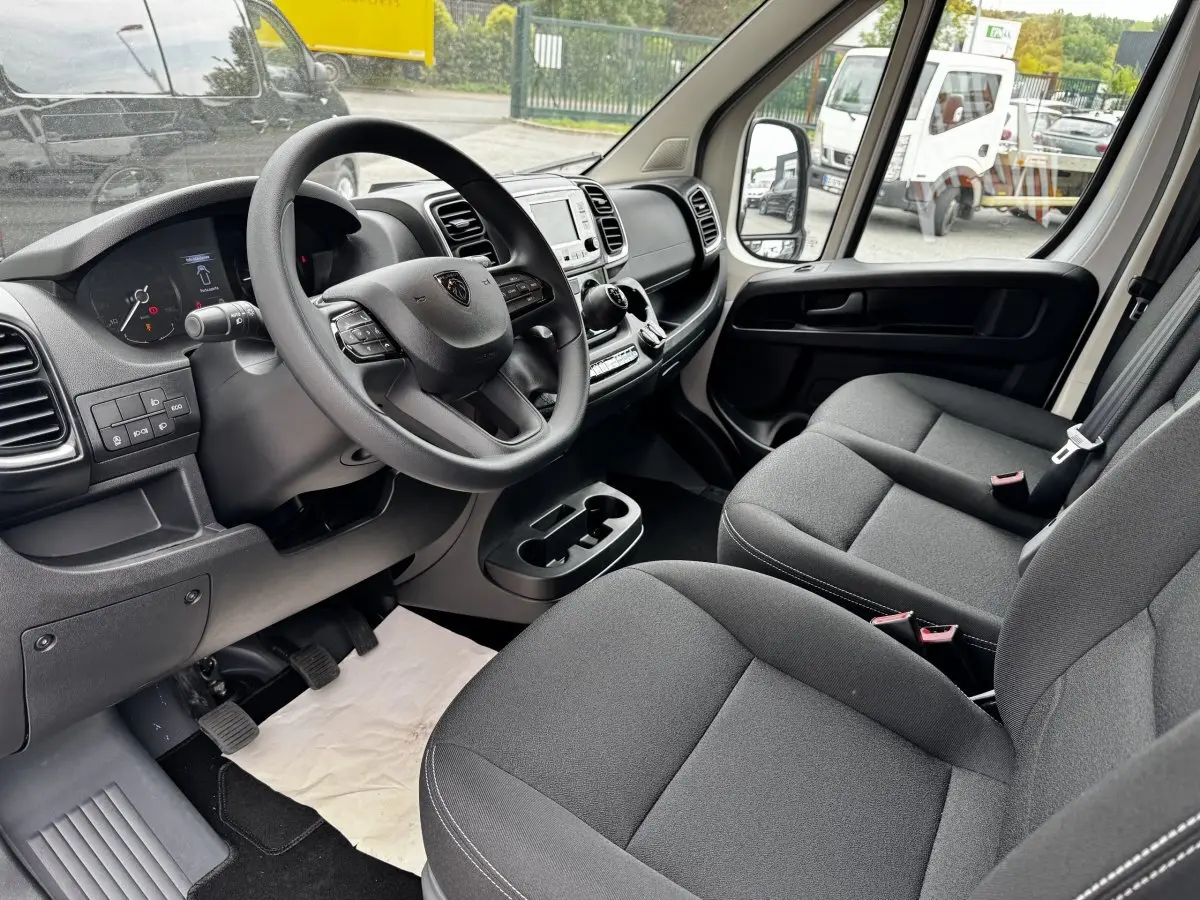 Intérieur du Peugeot Boxer Fourgon L2H1 2026 vu côté conducteur, montrant tableau de bord et sièges gris foncé.