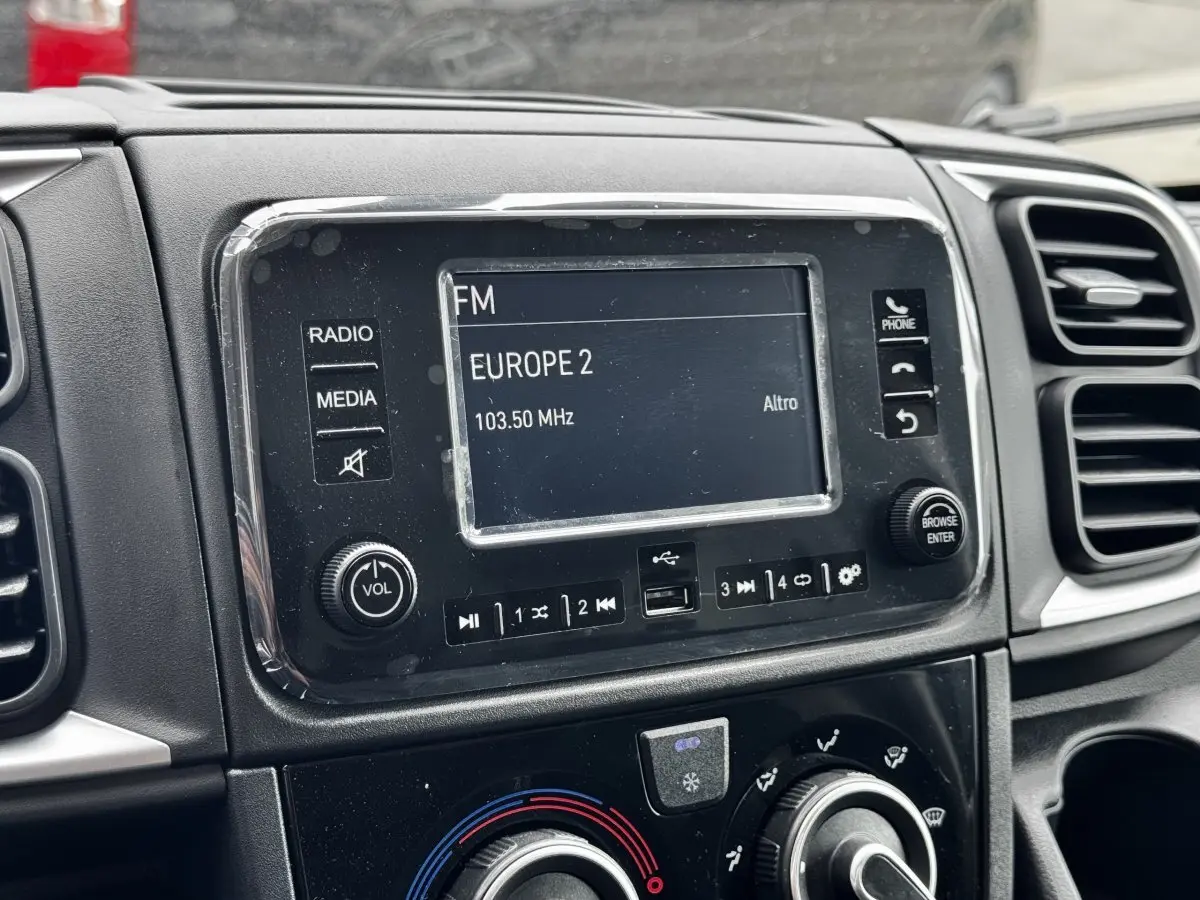 Gros plan sur l’écran multimédia et la console centrale noire du Peugeot Boxer Fourgon blanc, intérieur avant.