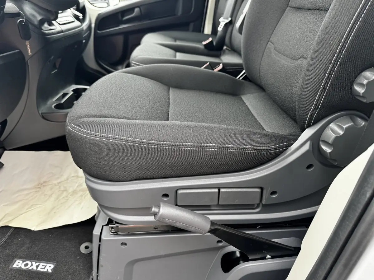 Gros plan sur le siège avant droit gris foncé du Peugeot Boxer Fourgon blanc, avec frein à main manuel visible.