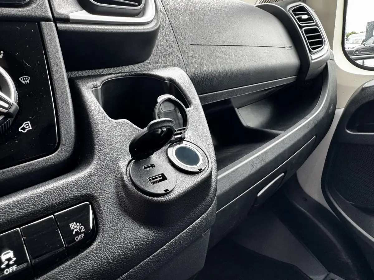 Détail intérieur côté passager du Peugeot Boxer Fourgon blanc 2026 montrant prise USB et port 12V ouverts sur tableau de bord.