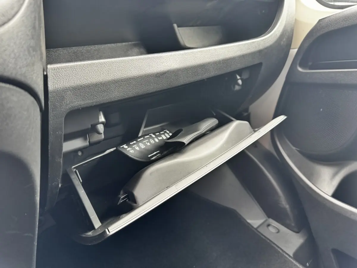 Gant de boîte à gants ouvert côté passager dans un Peugeot Boxer Fourgon blanc, montrant un manuel et un rangement intérieur.
