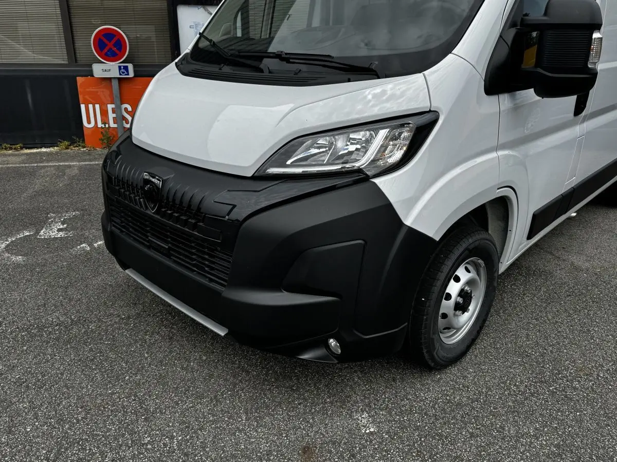 Vue 3/4 avant droit du Peugeot Boxer Fourgon blanc avec pare-chocs noir et phares modernes halogènes.