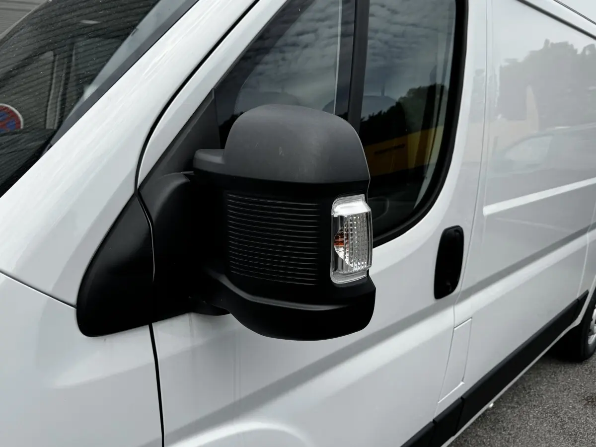 Gros plan sur le rétroviseur noir côté conducteur du Peugeot Boxer Fourgon blanc, vue latérale avant droite.