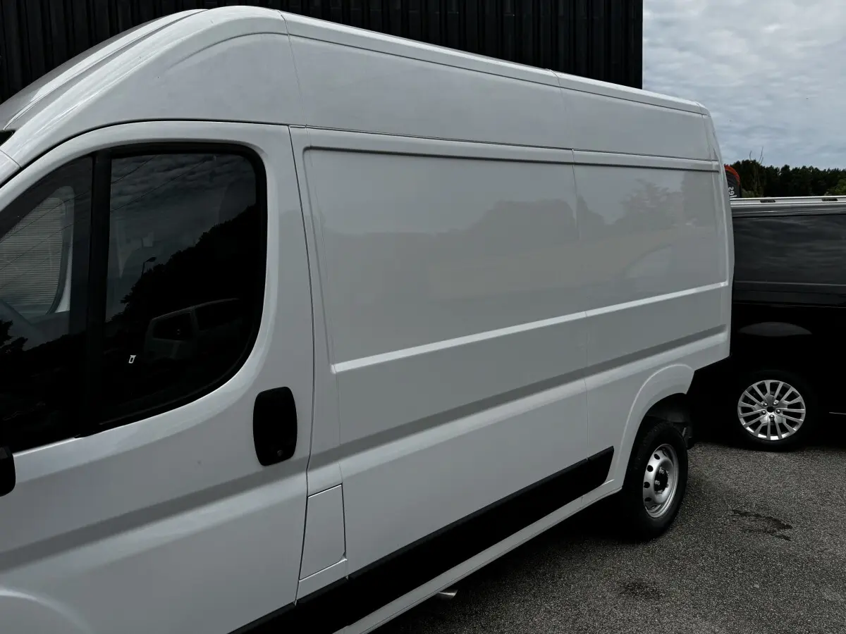 Vue de côté droit d’un Peugeot Boxer Fourgon blanc, version L2H1, avec porte latérale pleine et jante acier simple.