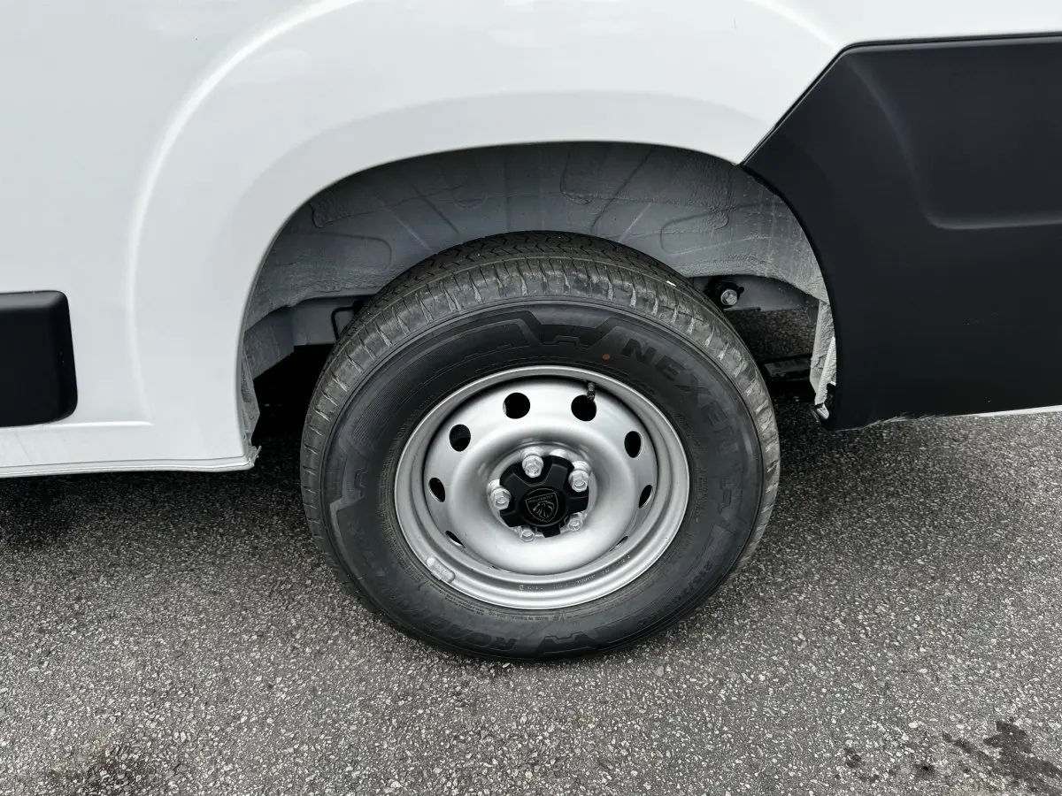 Gros plan sur la roue avant droite d’un Peugeot Boxer Fourgon blanc avec jante acier et logo Peugeot central.