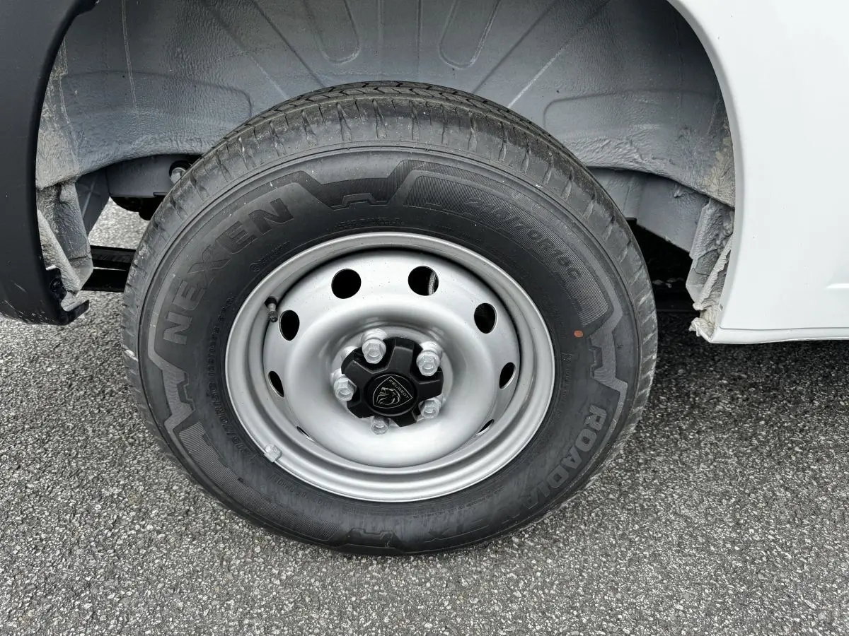 Gros plan sur la roue avant droite du Peugeot Boxer Fourgon blanc, jante acier avec logo Peugeot central.