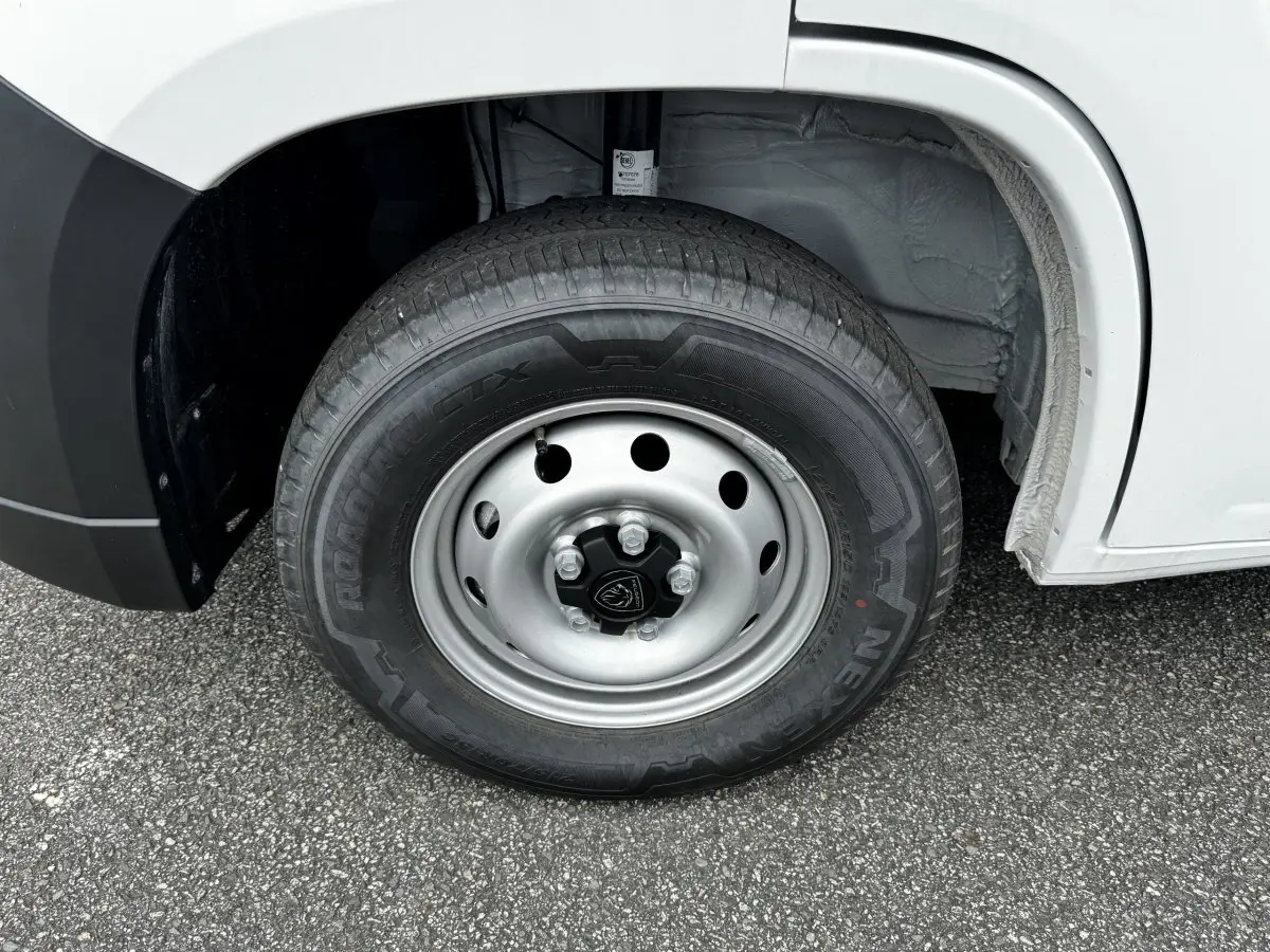 Gros plan sur la roue avant droite en jante acier du Peugeot Boxer Fourgon blanc, montrant le pneu et l'arche de roue.