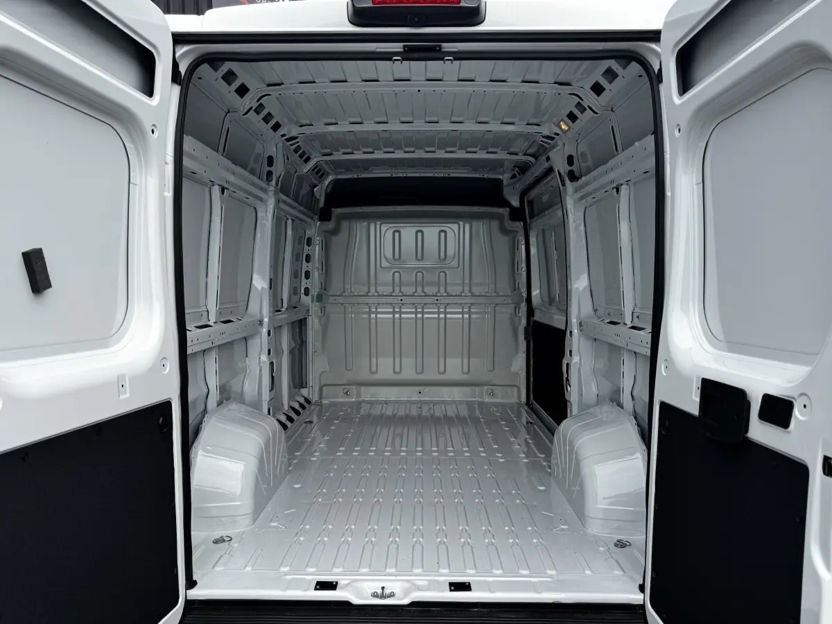 Vue intérieure arrière du fourgon blanc Peugeot Boxer L2H1 2026, montrant l'espace de chargement vide et la cloison pleine.
