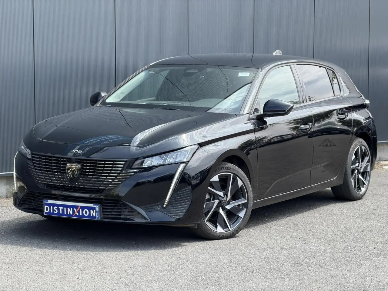 Peugeot 308 Hybrid 145 noire Perla vue 3/4 avant droit, avec jantes alliage 17'' et signature lumineuse LED.