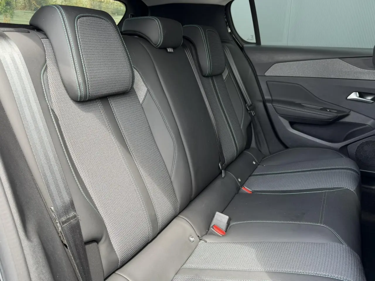 Vue intérieure côté droit des sièges arrière noirs avec surpiqûres bleues du Peugeot 308 Hybrid 145 e-DSC6 Allure 2025.
