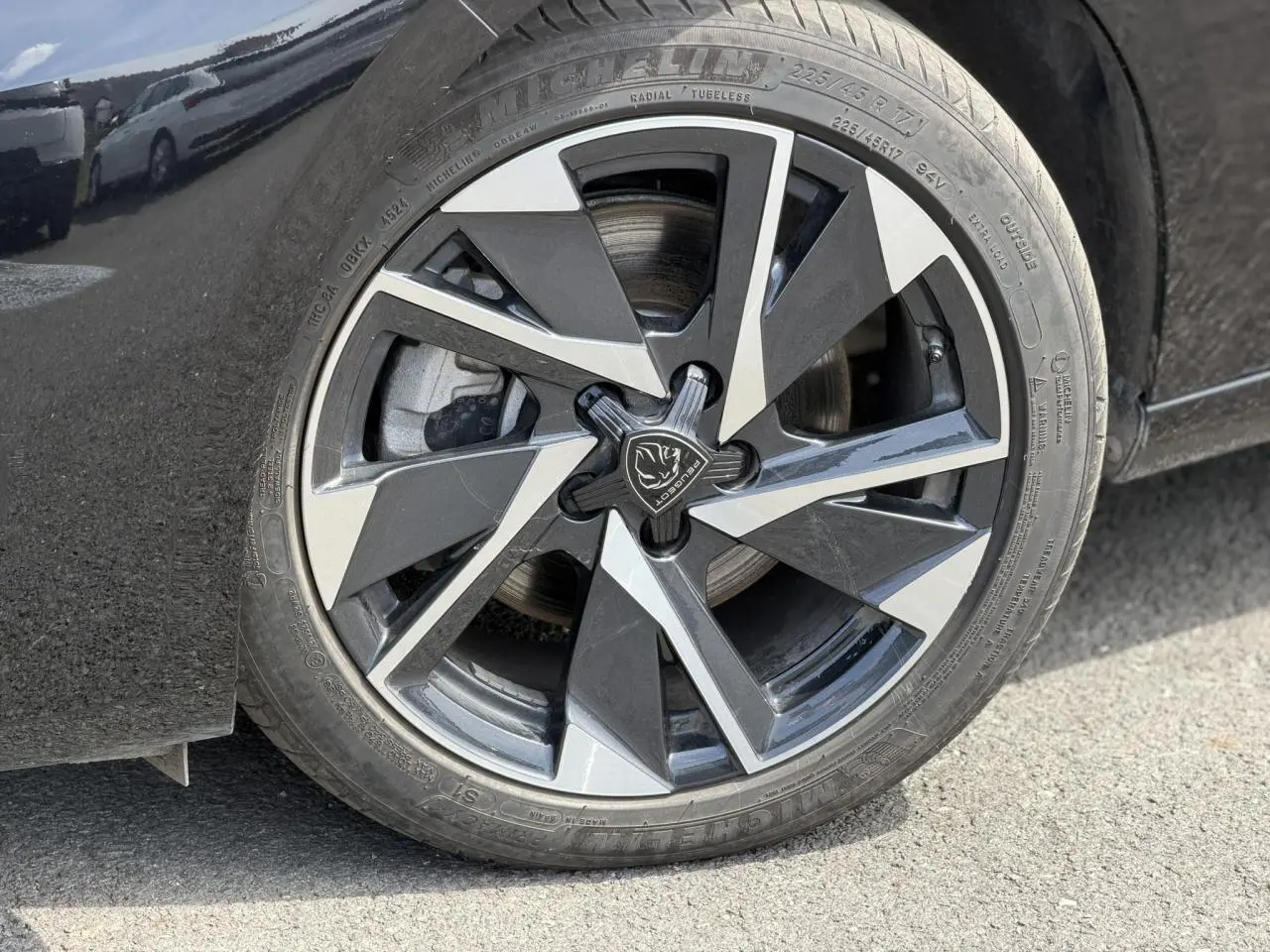 Gros plan sur la jante alliage 17'' Halong diamantée noire et argentée du côté gauche d'une Peugeot 308 Hybrid 2025 noir Perla.