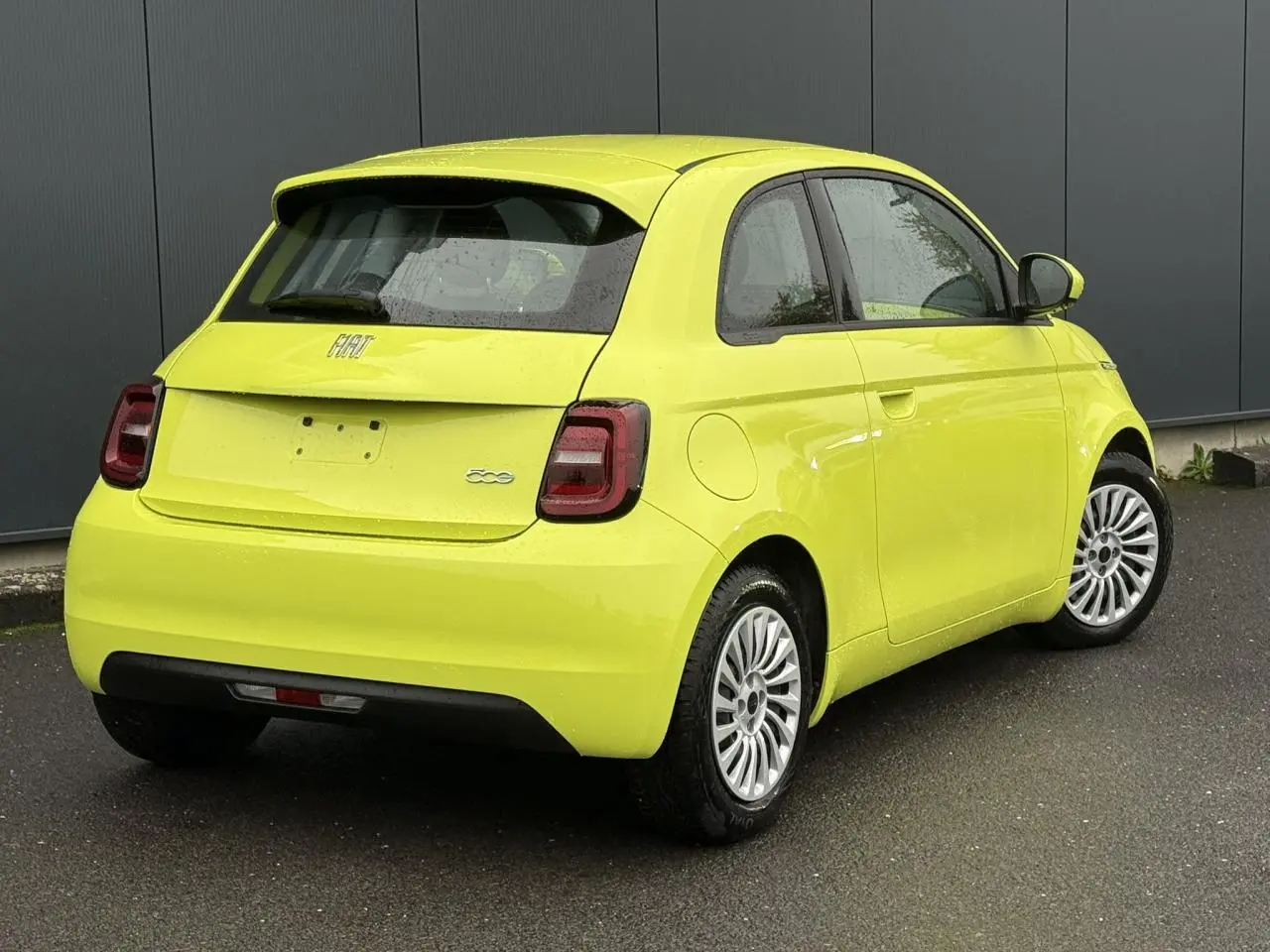 Vue 3/4 arrière droite d'une Fiat 500 électrique 2024 en jaune Acid, avec feux arrière LED et jantes argentées.