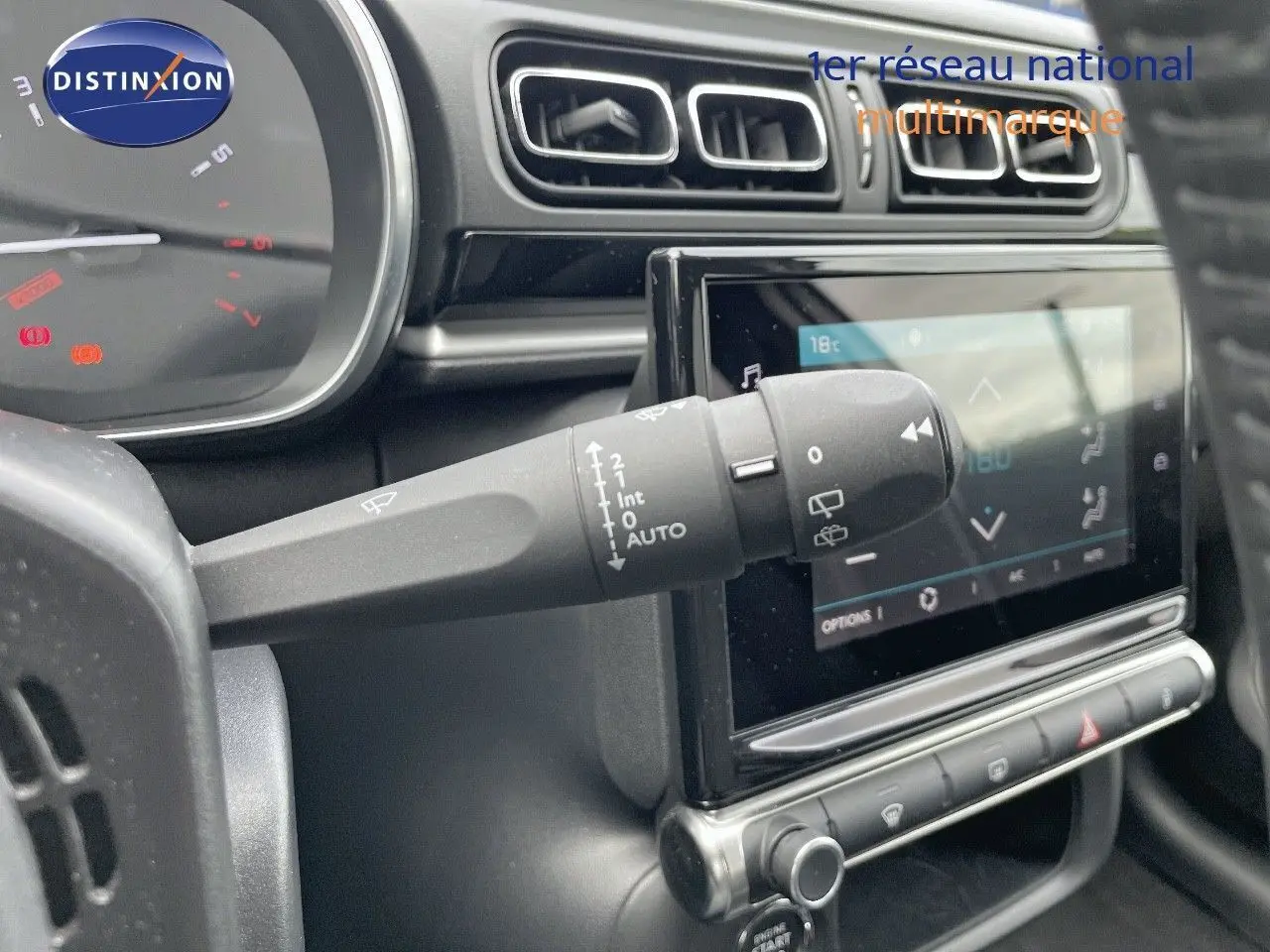 Gros plan sur la commande d'essuie-glace à gauche du volant dans l'habitacle gris noir d'une Citroën C3 2021.