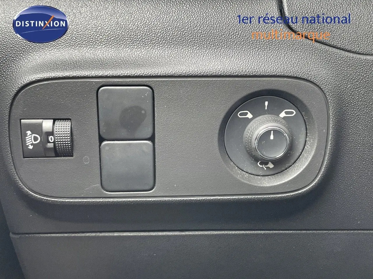 Gros plan sur les commandes de réglage des rétroviseurs et du niveau des phares dans une Citroën C3 gris Artense.