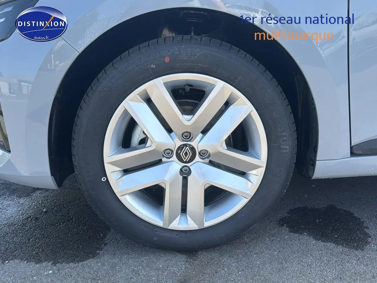 Gros plan sur la roue avant gauche d'une Renault Clio V gris rafale avec jante alliage 16 pouces et logo Renault central.