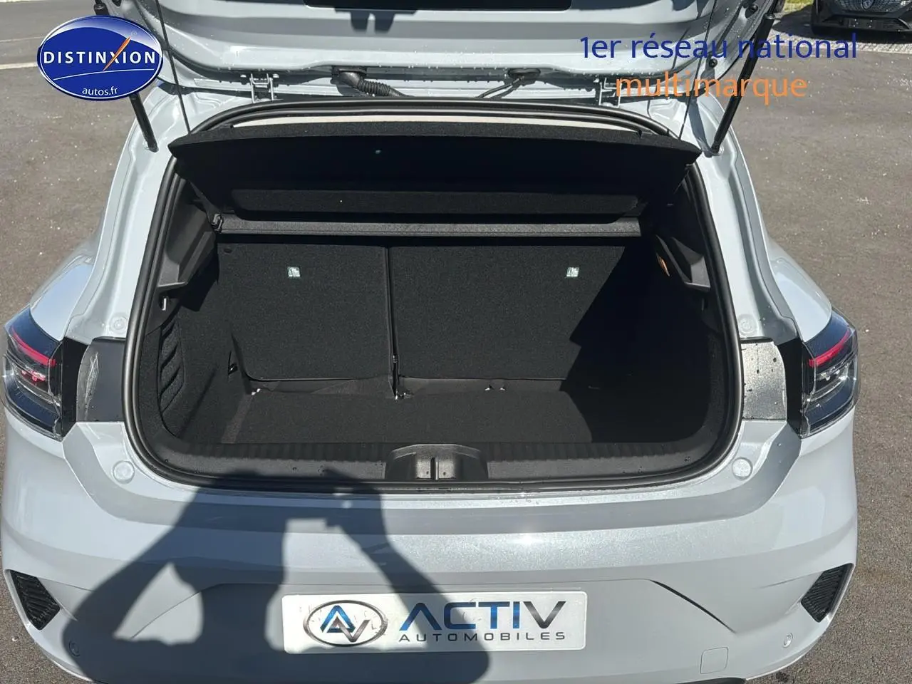 Coffre ouvert d'une Renault Clio V gris rafale vue arrière, soulignant l'espace de chargement vide.