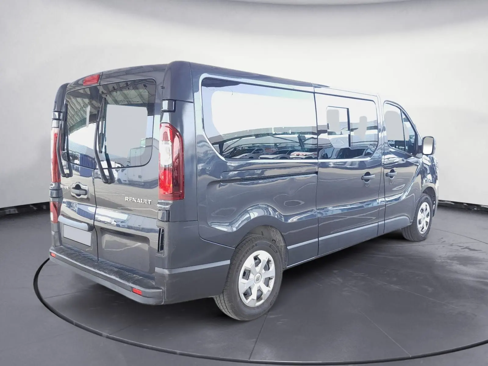 Renault Trafic Combi gris foncé métal vu en 3/4 arrière droit, avec vitres latérales et portes arrière vitrées.