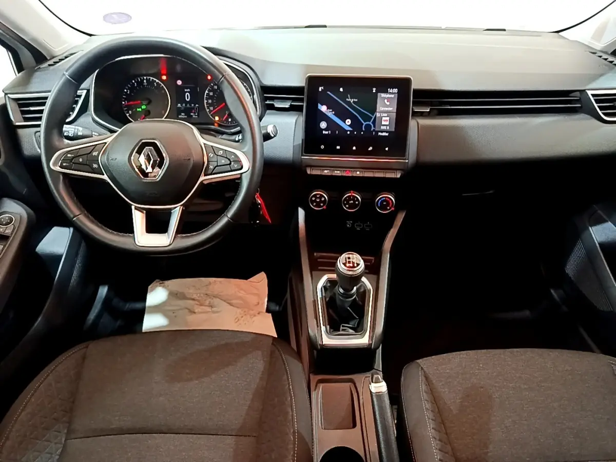 Vue frontale de l'habitacle de la Renault Clio Business TCe 100 2019 avec volant cuir, écran tactile et levier de vitesses manuel.