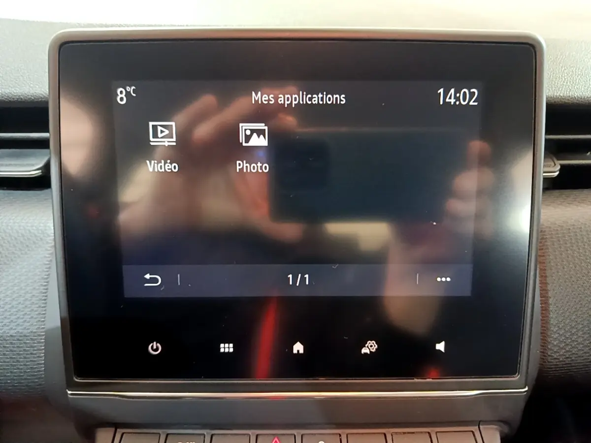 Écran tactile central affichant les applications vidéo et photo sur tableau de bord Renault Clio blanc, vue intérieure frontale.